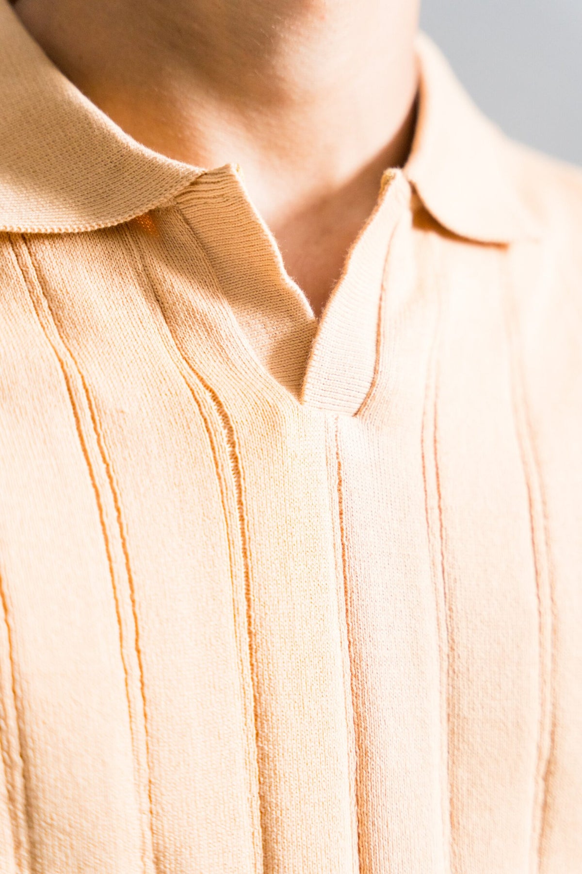 Close-up of Wear Anarchy Apricot Knitted Polo showing open collar and vertical textured knit detailing