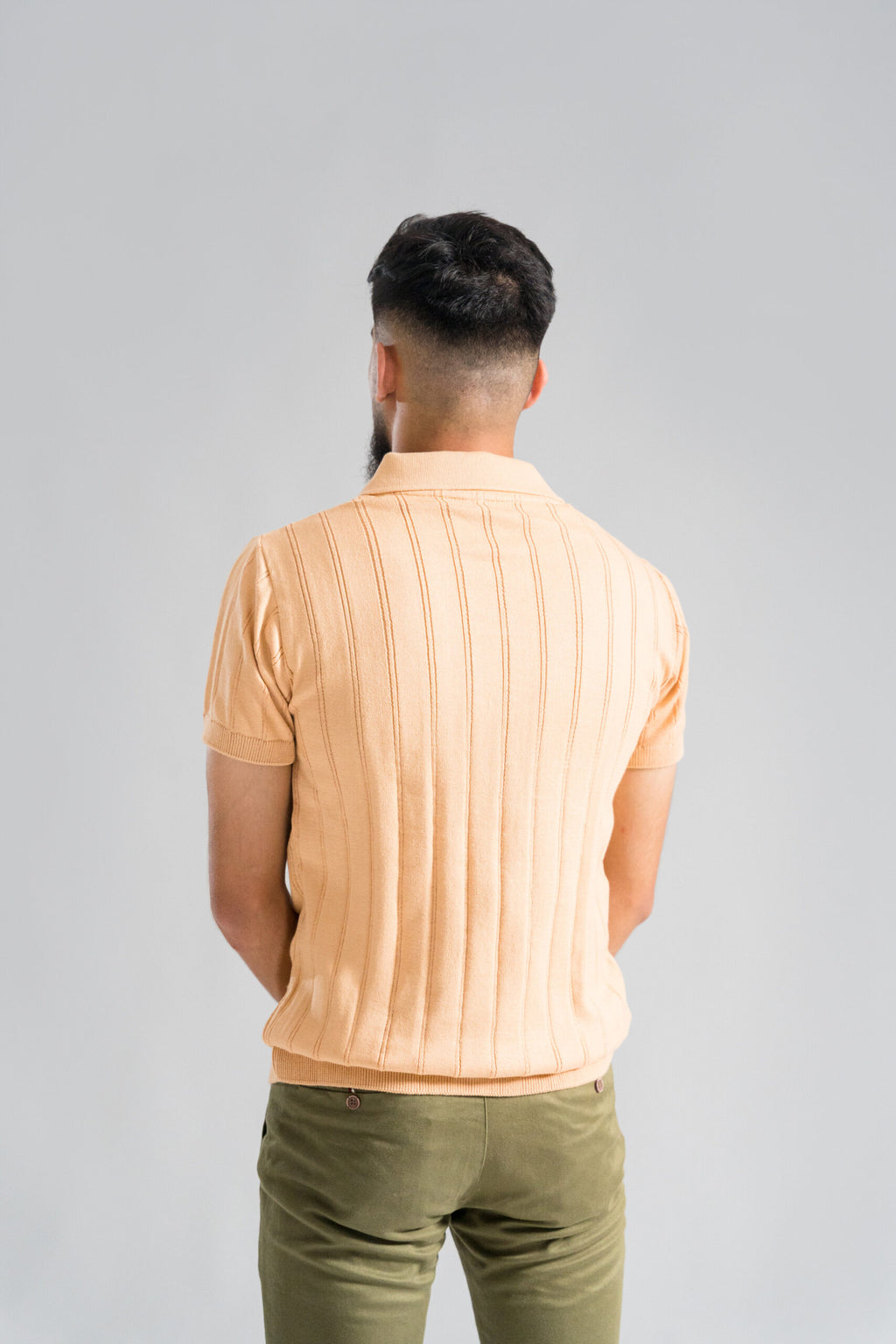 Back view of Wear Anarchy Apricot Knitted Polo for men showing vertical knit pattern, short sleeves and ribbed hem