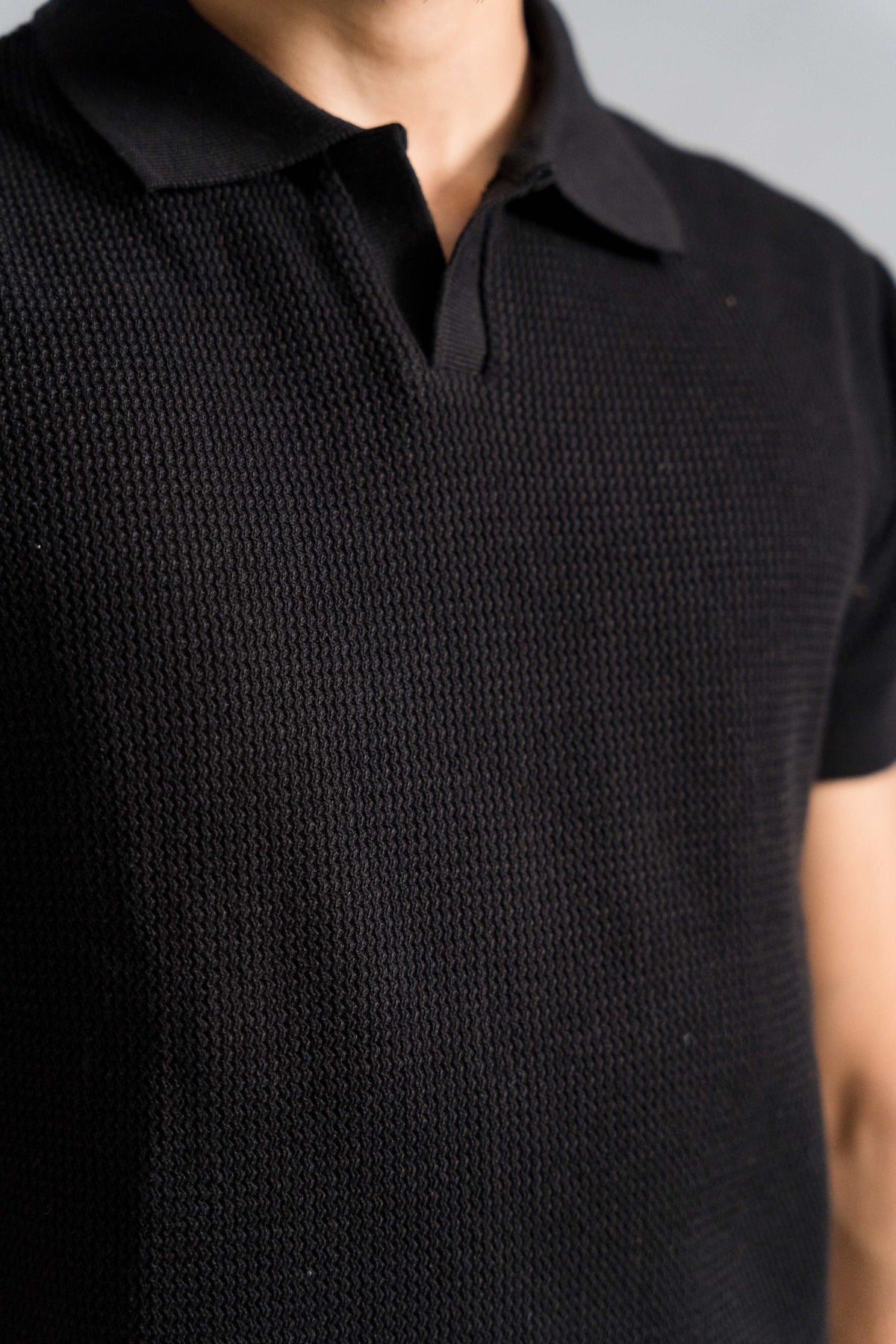 Close-up of Wear Anarchy Black Knitted Polo showing open collar and textured knit fabric detail