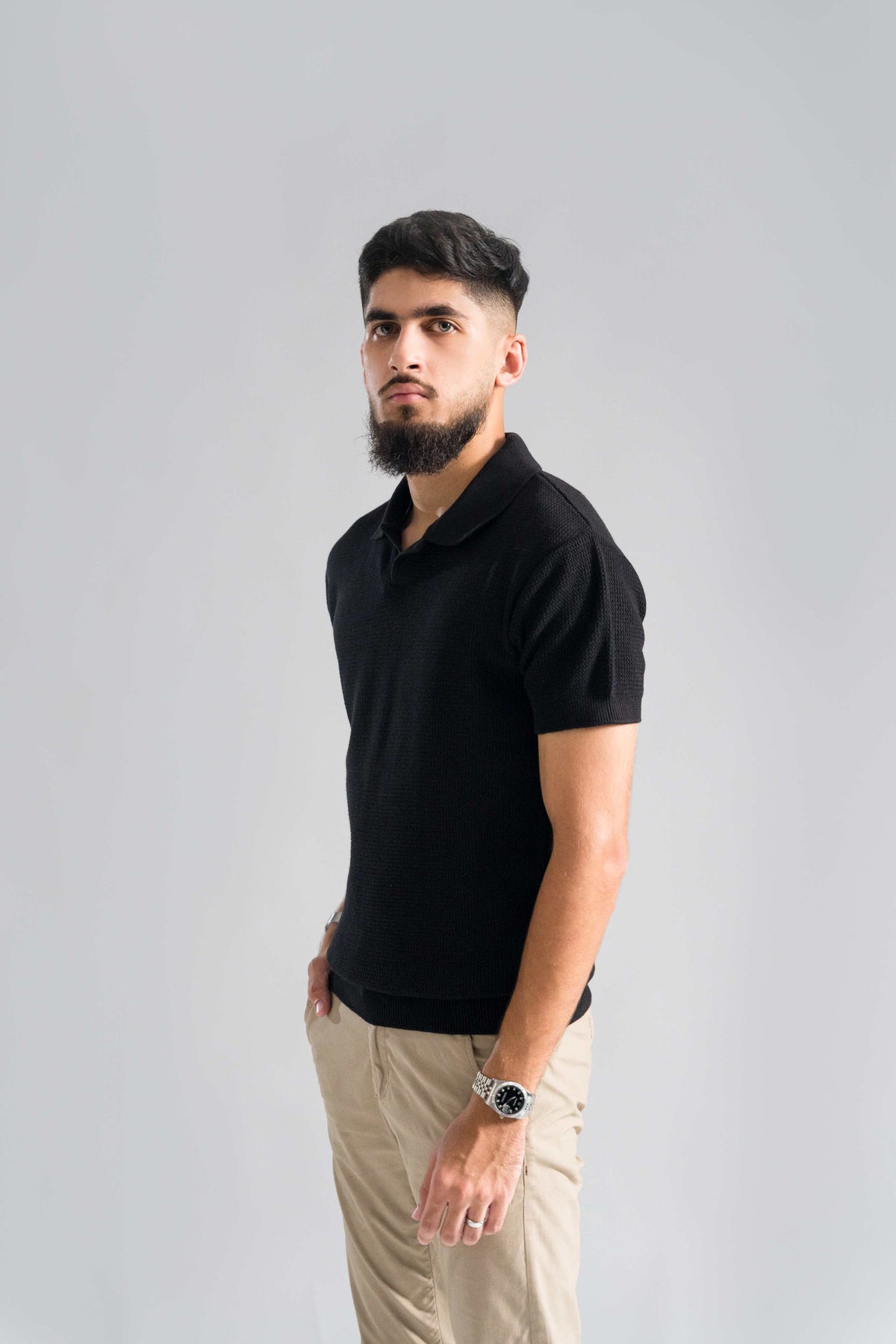 Side view of Wear Anarchy Black Knitted Polo for men with textured knit fabric, short sleeves and open collar