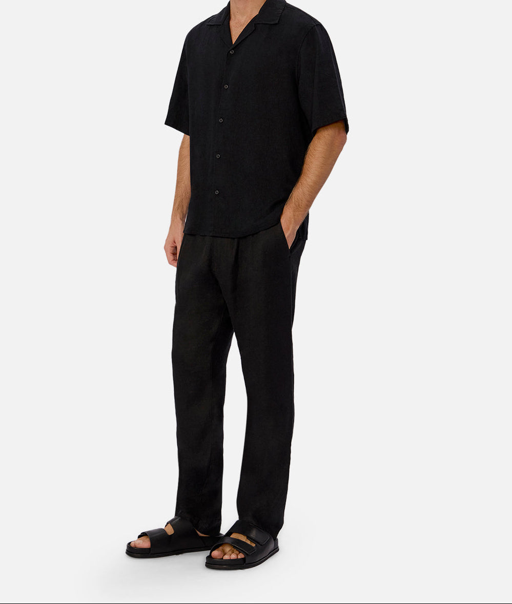 Side view of Wear Anarchy black short-sleeve button-up shirt for men styled with black trousers and sandals