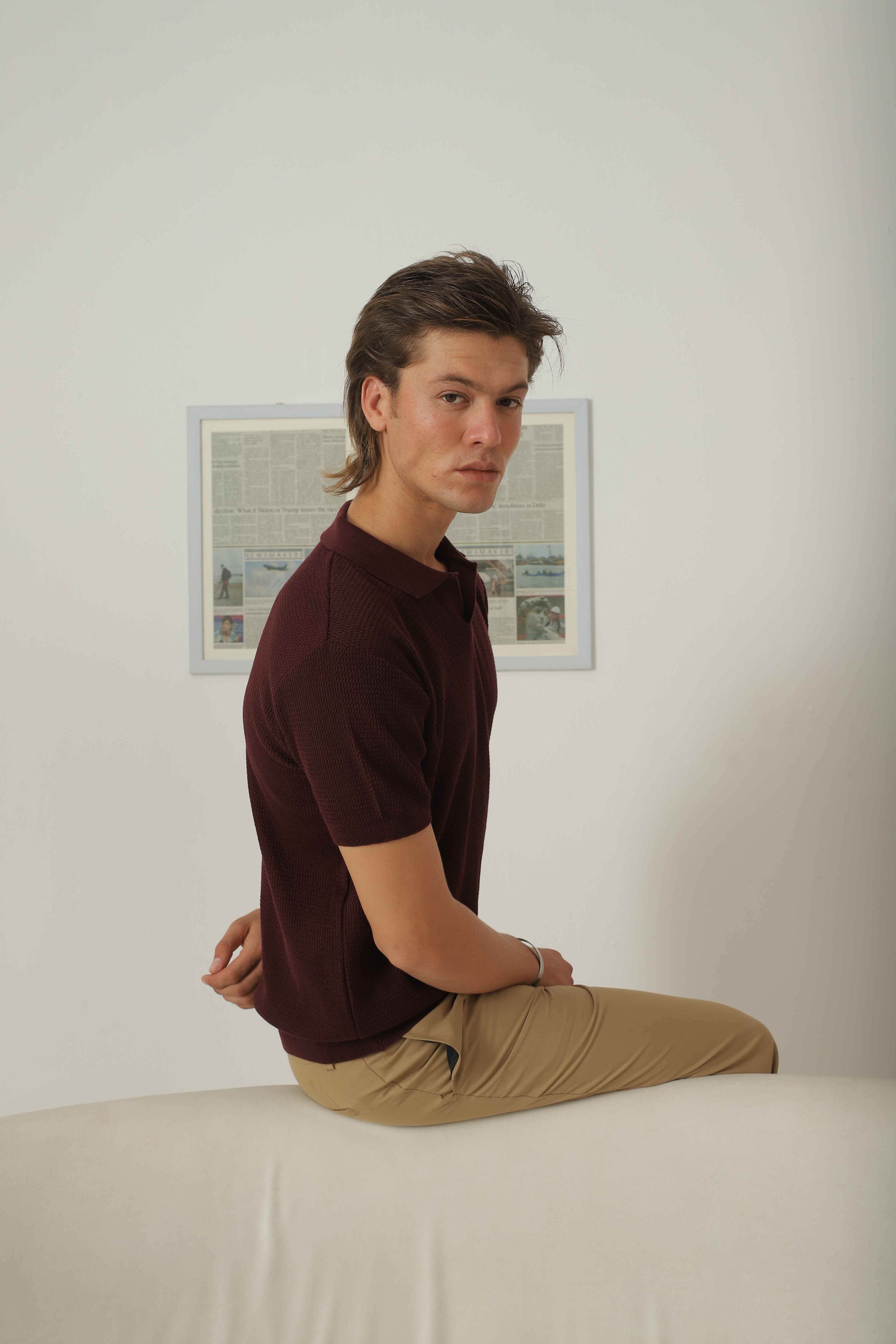 Side seated view of Wear Anarchy burgundy knitted polo shirt for men styled with beige trousers