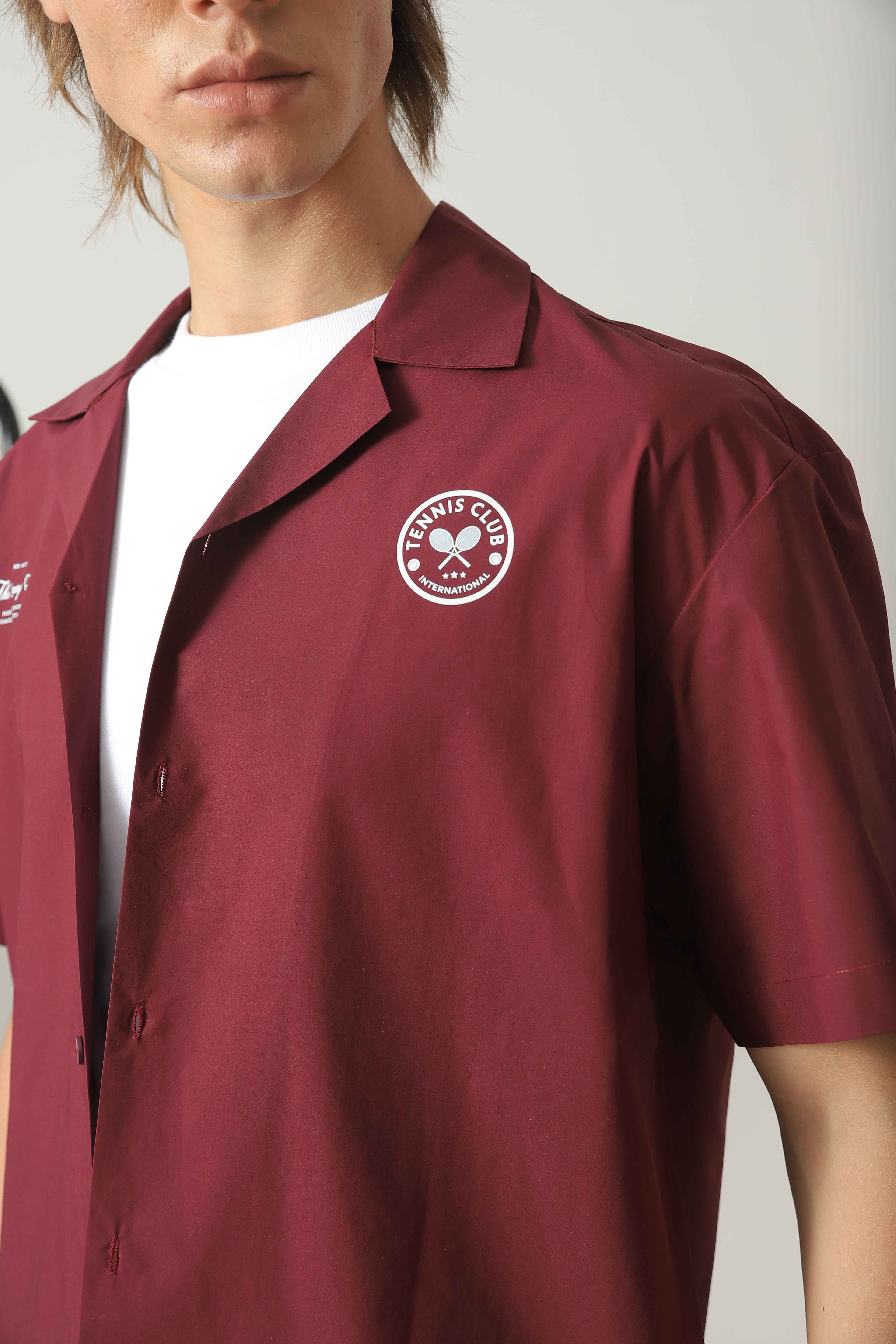 Close-up of Wear Anarchy maroon golf resort shirt showing open collar, short sleeve and embroidered tennis club chest detail