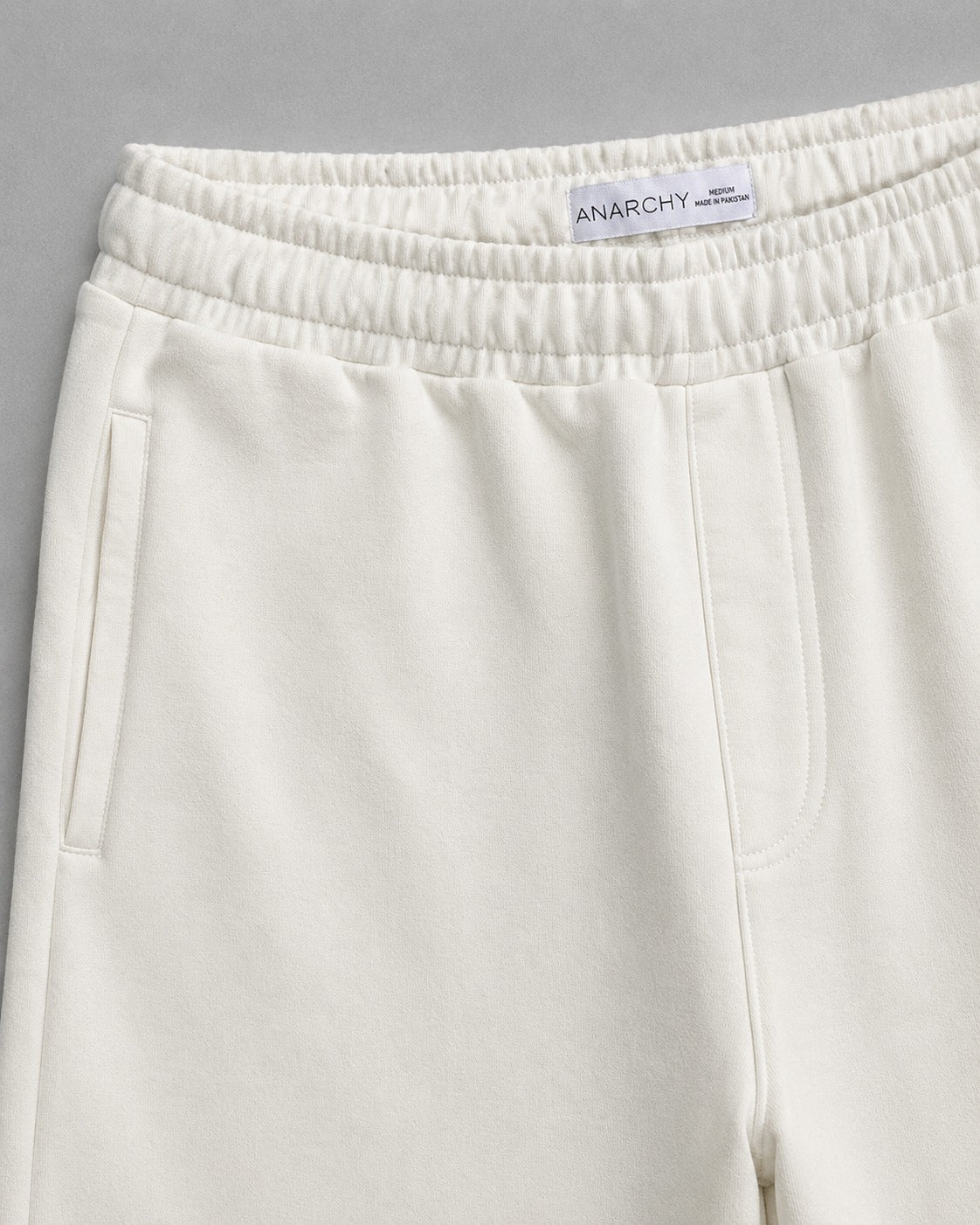 Close-up of Wear Anarchy off-white terry trousers showing elastic waistband, side pockets and soft terry fabric