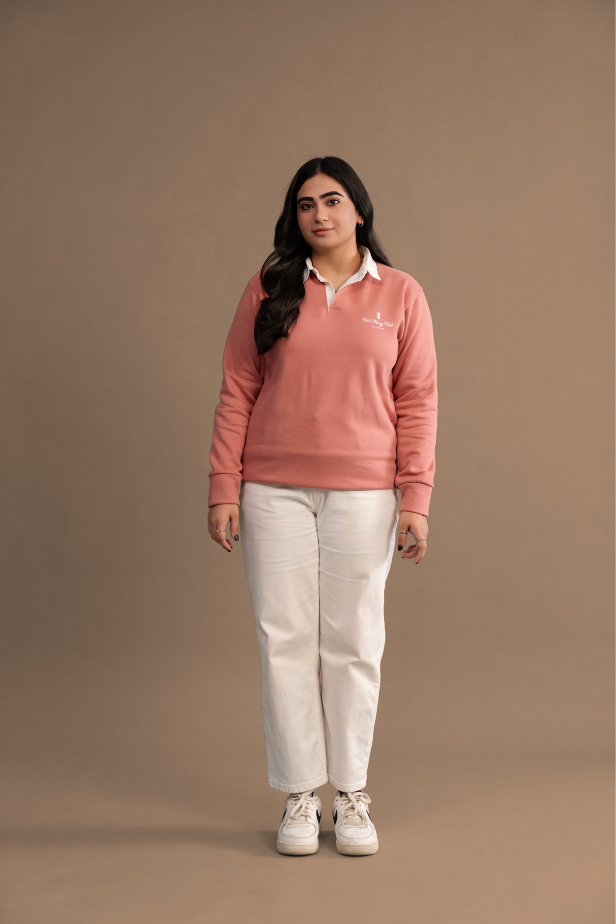 Wear Anarchy Pink Rugby Sweatshirt styled with white trousers and sneakers in a women’s full-length look