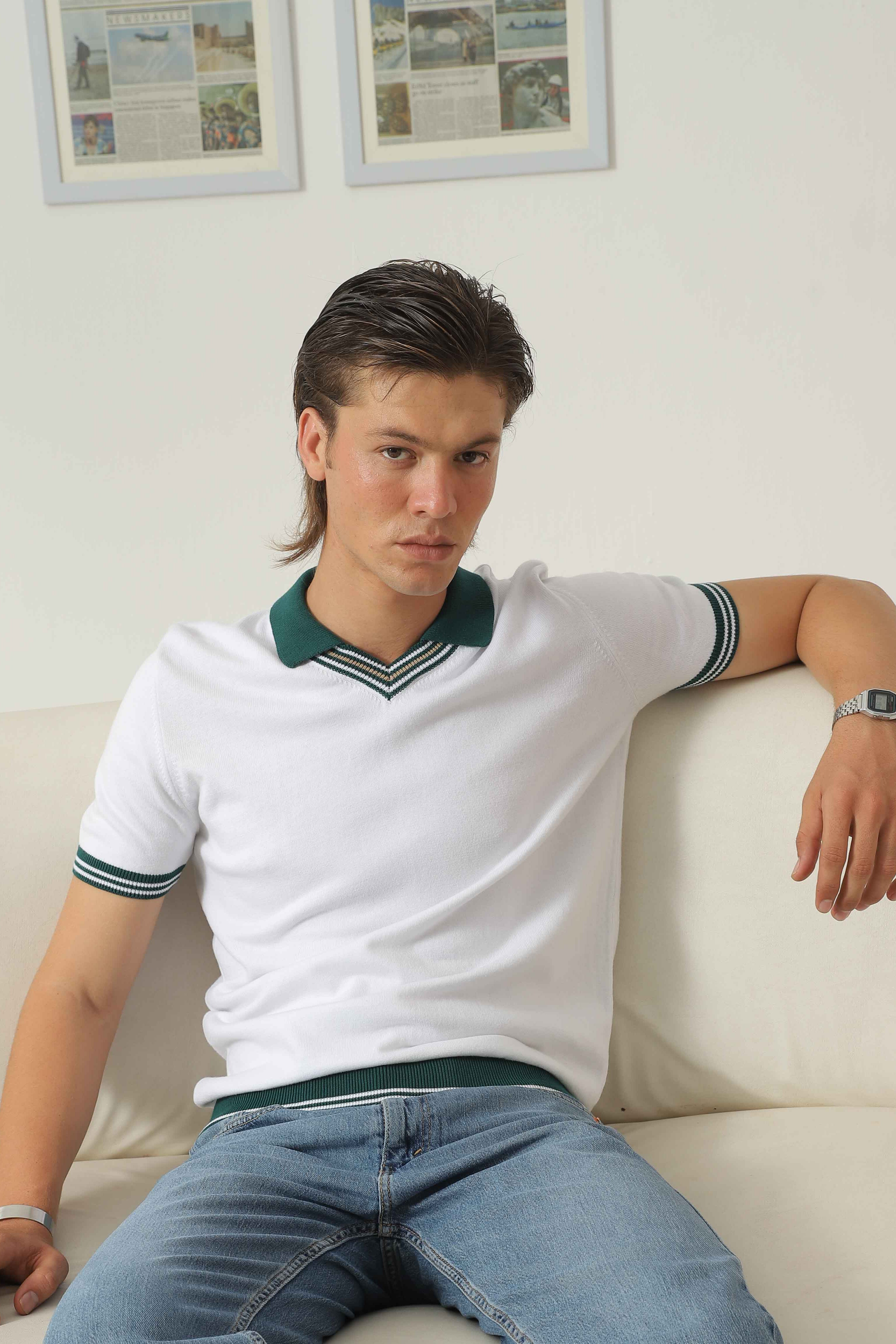 Wear Anarchy white knit polo shirt for men with green contrast collar and striped trim styled with blue jeans in a seated look
